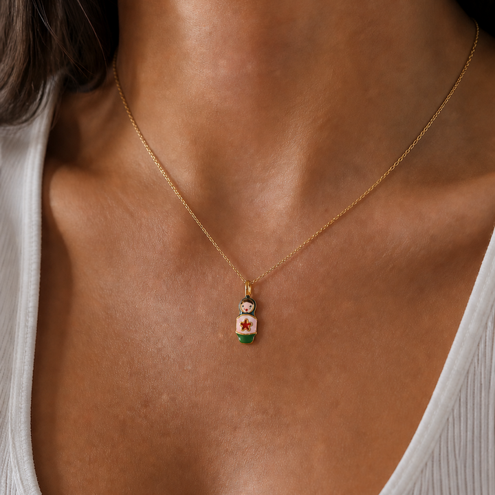 Gold necklace with a small pendant on a person wearing a white top.