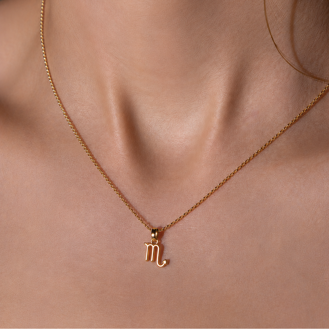 Gold necklace with a Scorpio symbol pendant on a person's neck