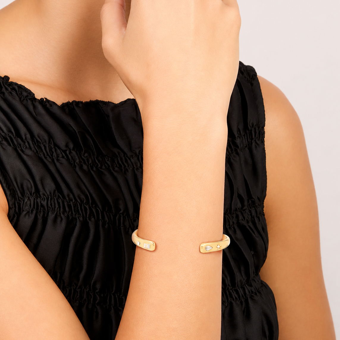 Gold bracelet on a person's wrist with a plain background