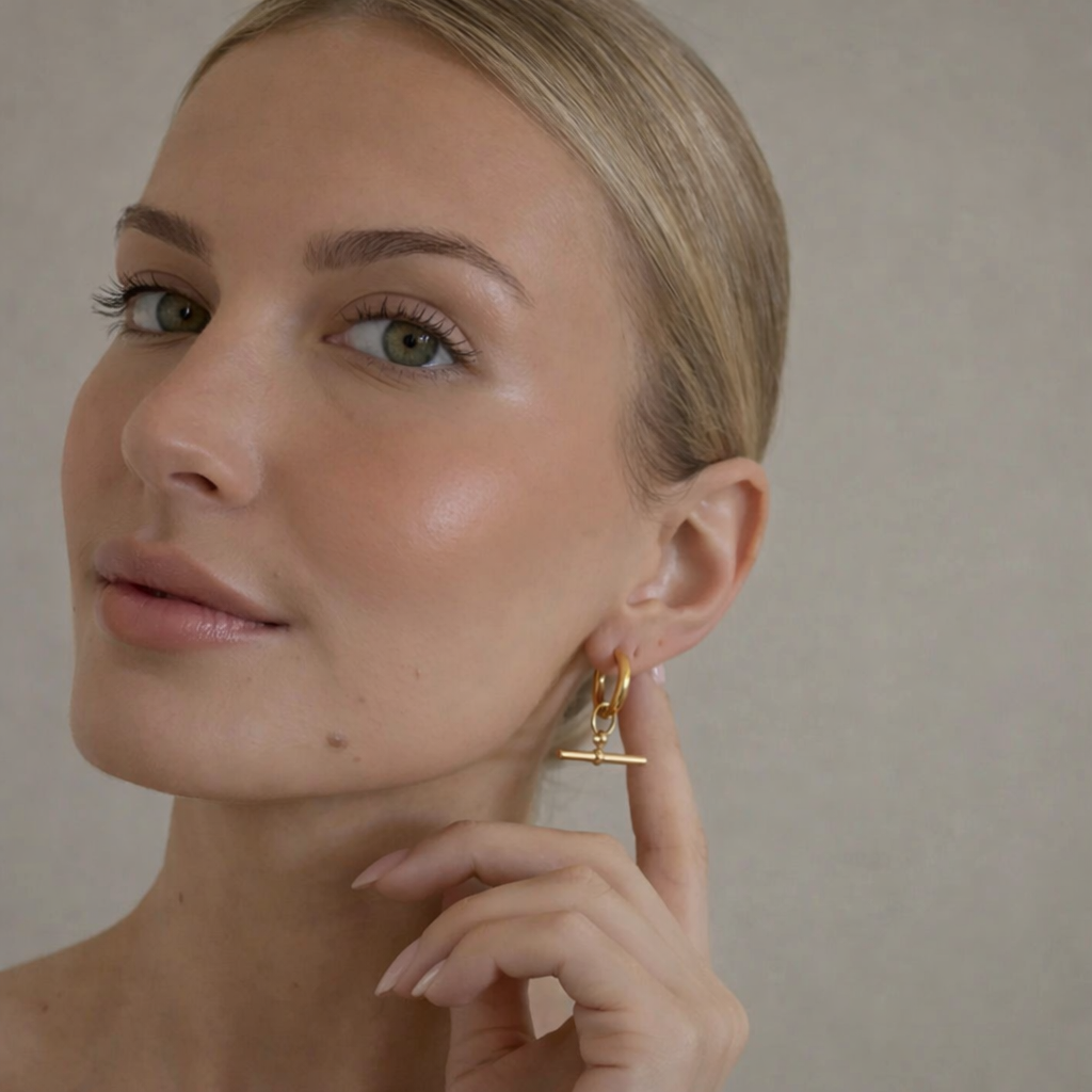 Woman wearing gold earrings against a neutral background