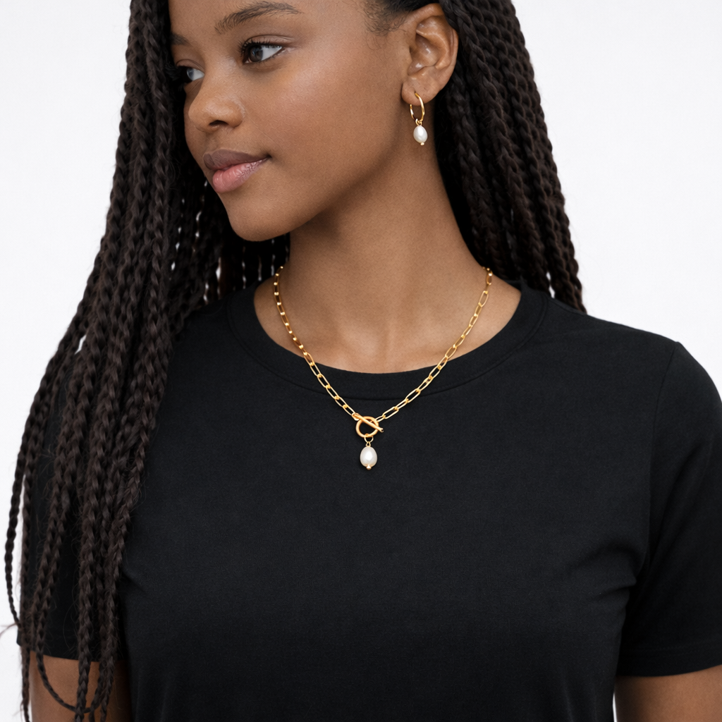 Woman wearing a gold necklace with pearl pendants on a plain background