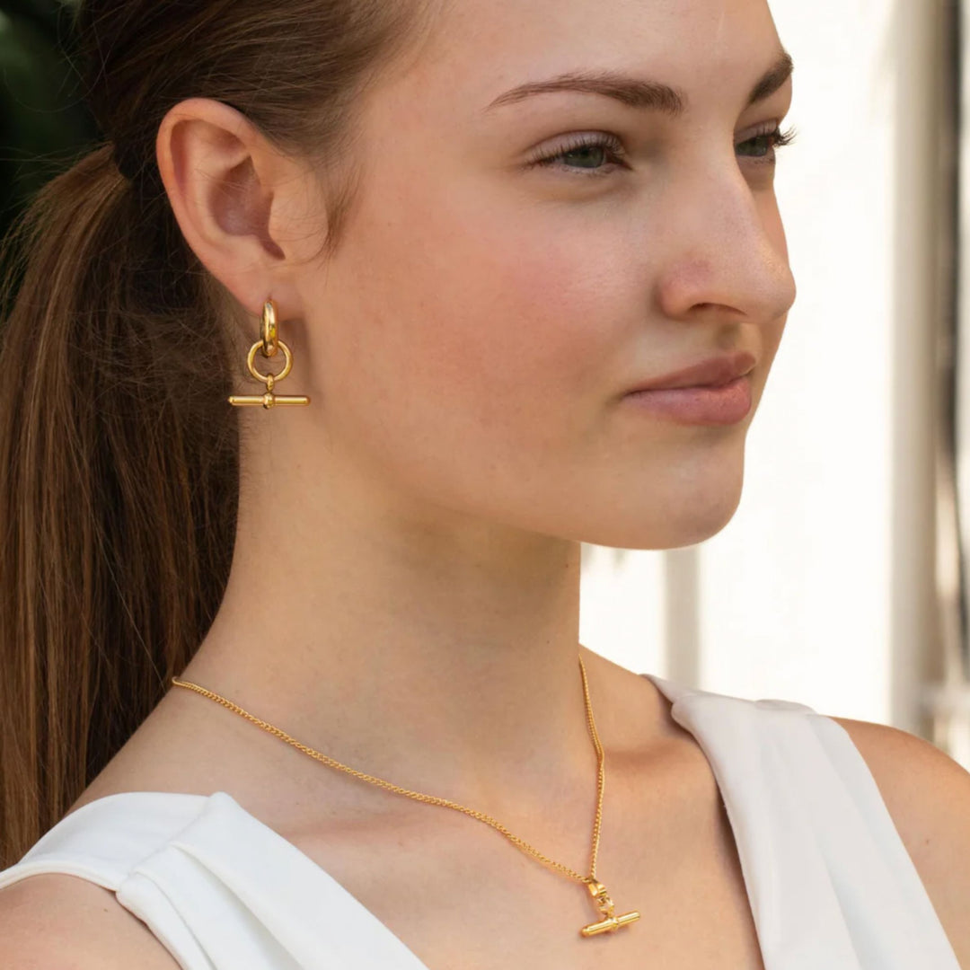 Woman wearing gold earrings and necklace with a blurred background