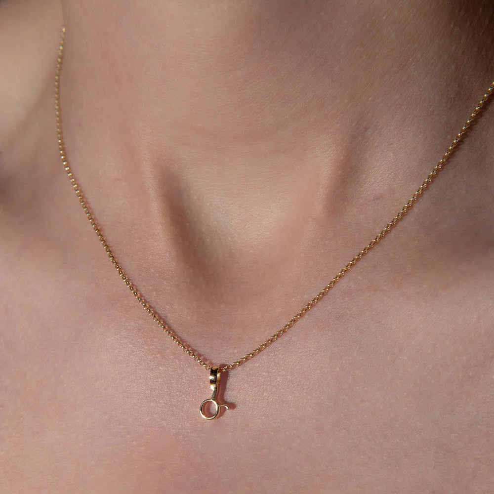 Rose gold necklace with a small pendant on a person's neck against a neutral background