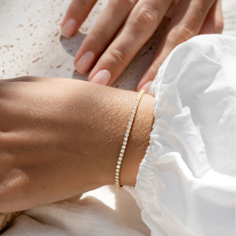 Close-up of a hand wearing a delicate bracelet on a light background