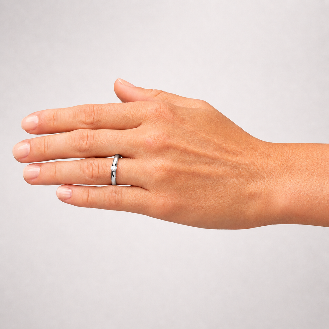 Hand wearing a silver ring on a plain background