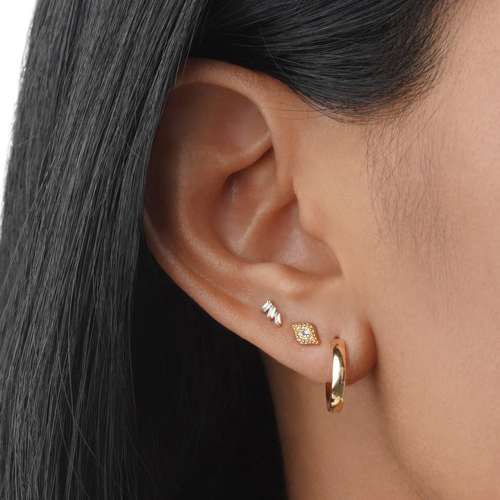 Close-up of an ear wearing gold hoop earrings with a blurred background
