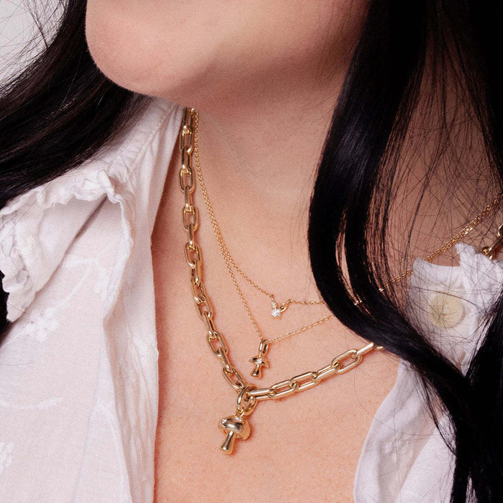 Close-up of a person wearing gold necklaces with various charms.