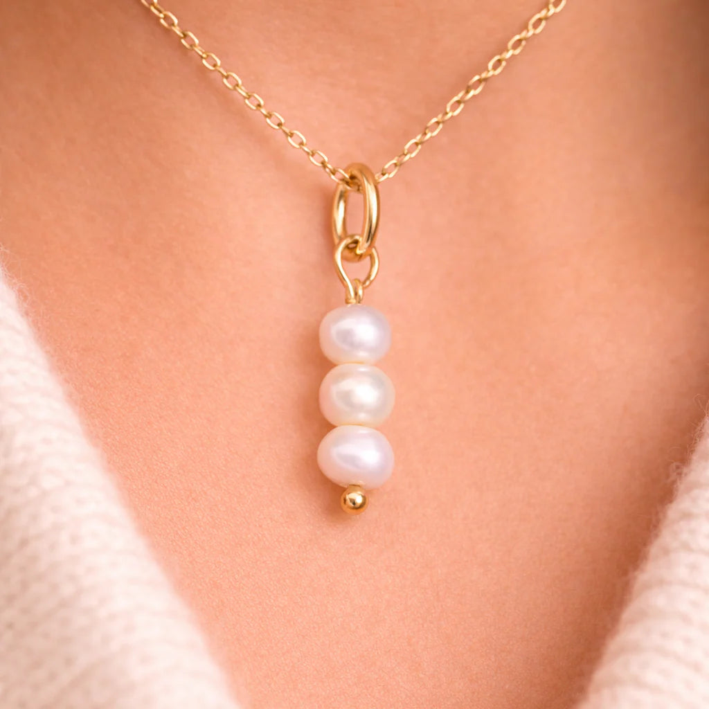 Gold necklace with a pearl pendant on a person's neck