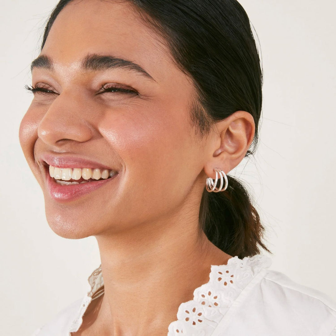 Woman wearing hoop earrings with a plain background