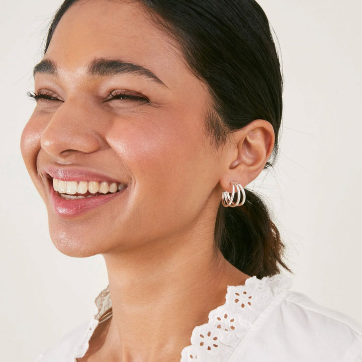 Woman wearing hoop earrings with a plain background