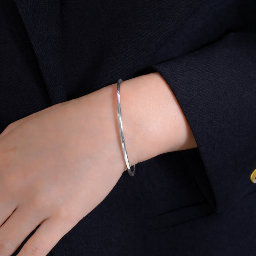 Silver bracelet on a person's wrist with a dark background