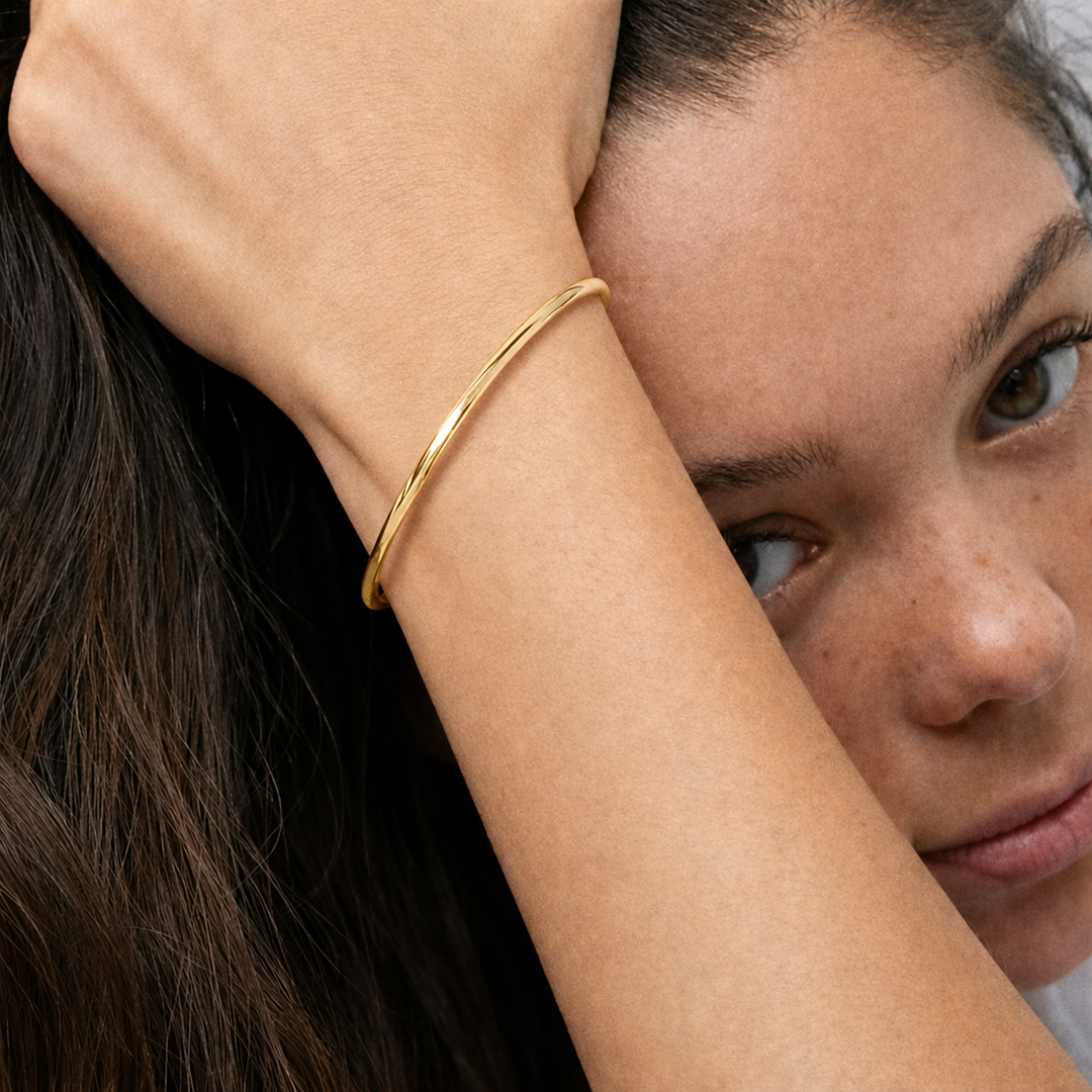 Woman wearing a gold bracelet with a neutral background