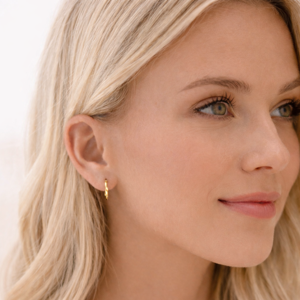 Close-up of a woman wearing a gold earring with a plain background