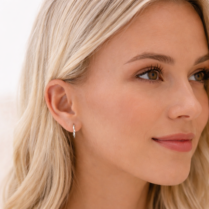 Close-up of a woman wearing a silver earring with a plain background