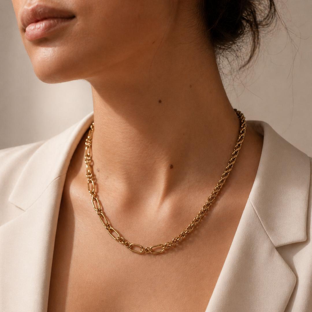 Close-up of a person wearing a gold chain necklace with a neutral background