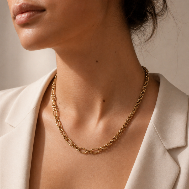 Close-up of a person wearing a gold chain necklace with a neutral background