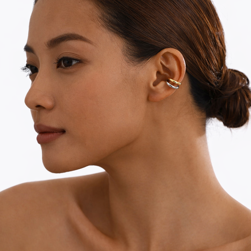 Close-up of a woman wearing a gold ear cuff on a white background