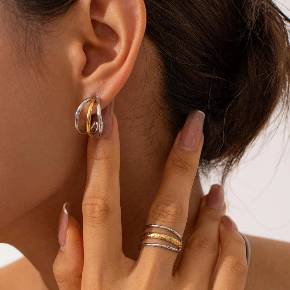 Close-up of an ear wearing a gold hoop earring with a hand adjusting the earring.