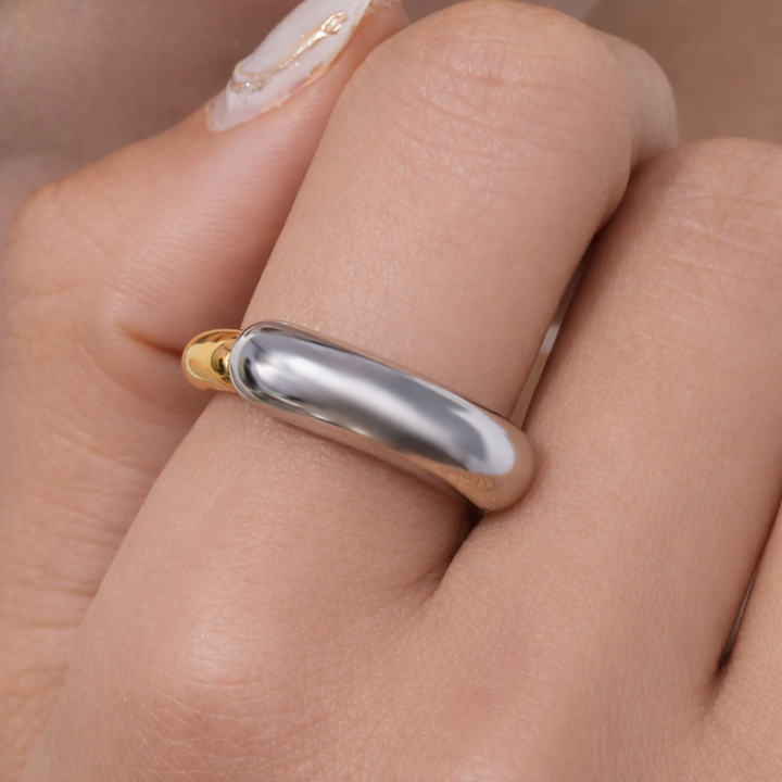 Silver ring with gold accent on a finger