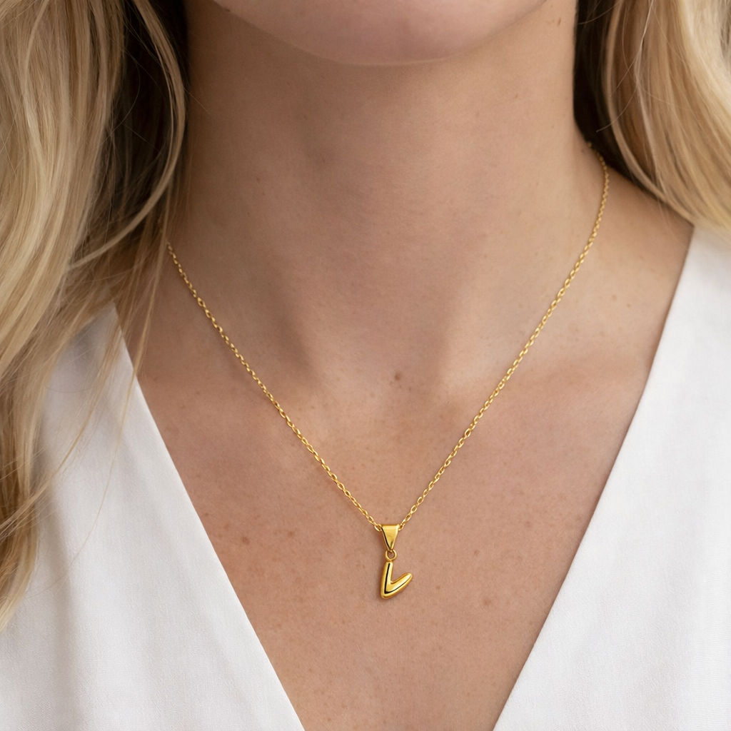 Gold necklace with a 'V' pendant worn by a person with blonde hair.