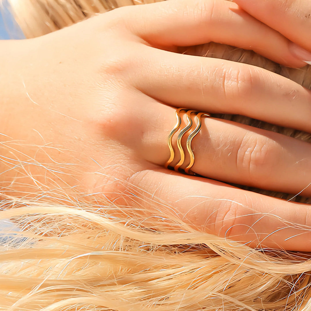 Close-up of a hand wearing a gold ring with a blurred background