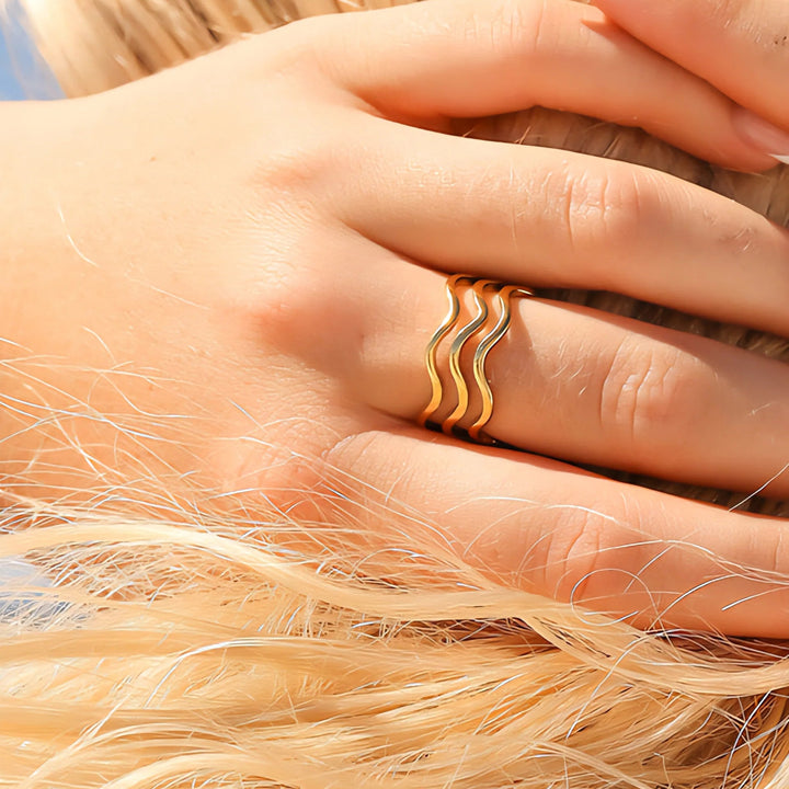 Close-up of a hand wearing a gold ring with a blurred background