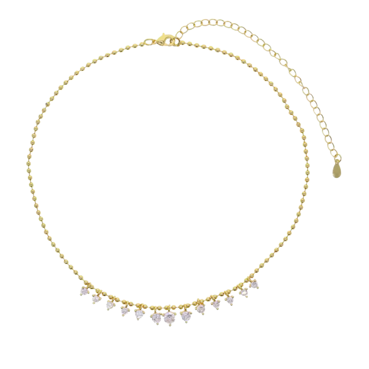 A gold beaded choker necklace with a row of small clear heart-shaped crystals hanging from the front, shown on a plain white background.