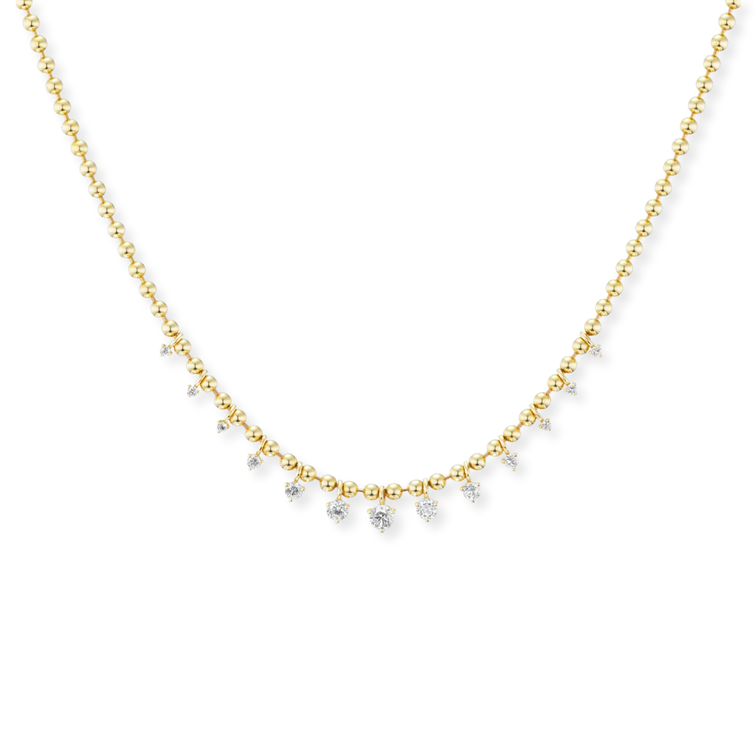 A delicate gold chain necklace featuring a curved row of small clear gemstones, photographed against a solid white background.