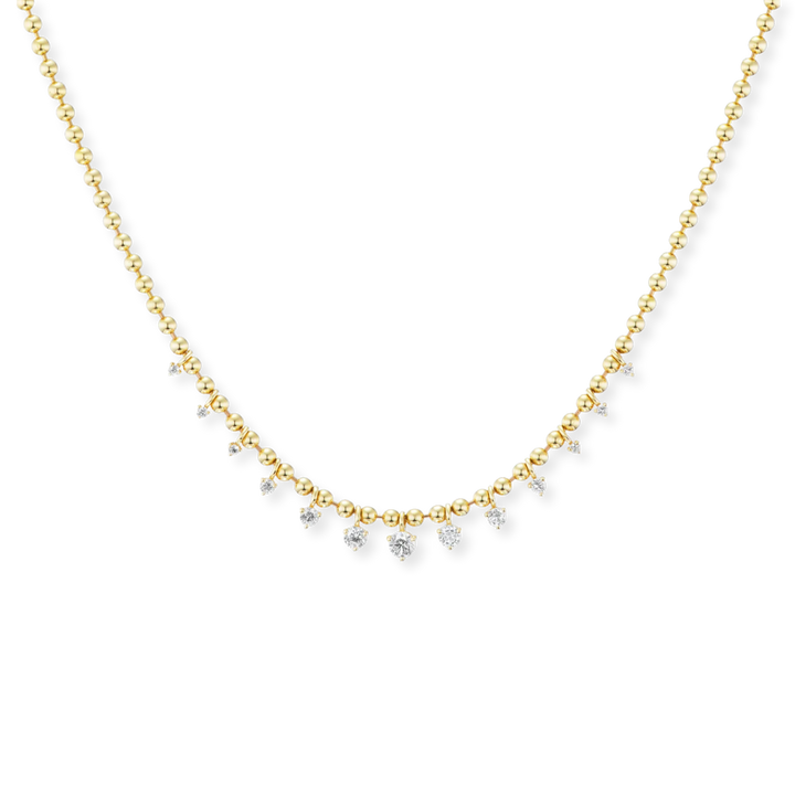 A delicate gold chain necklace featuring a curved row of small clear gemstones, photographed against a solid white background.