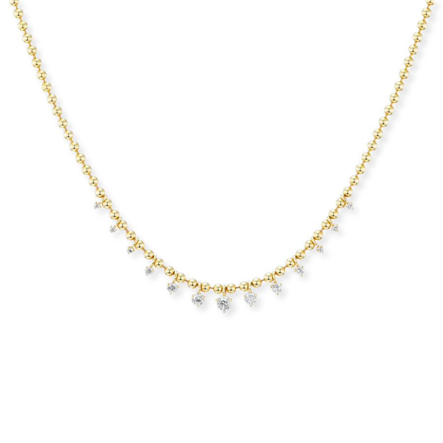 A delicate gold chain necklace featuring a curved row of small clear gemstones, photographed against a solid white background.