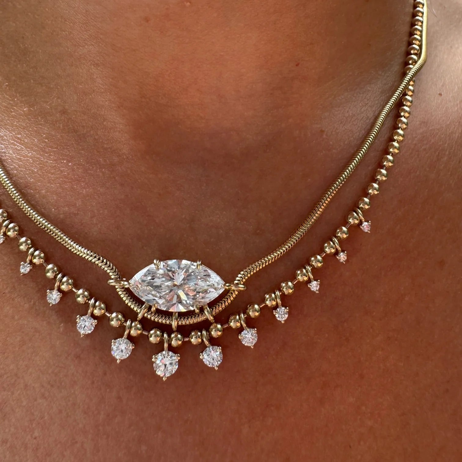 Gold necklace with a large diamond pendant on a person's neck