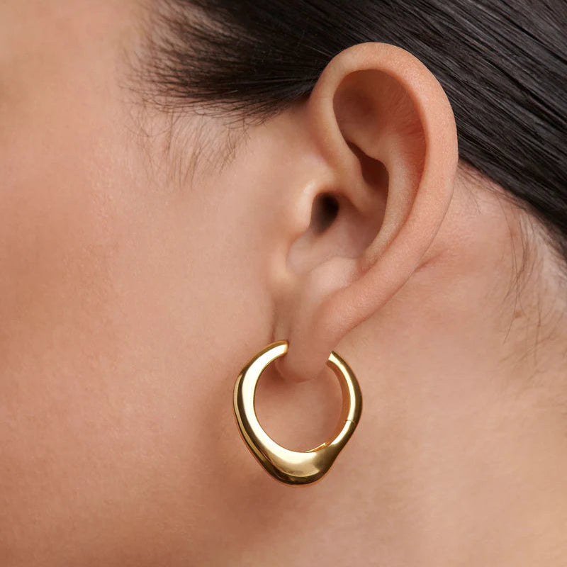 Gold hoop earring worn by a person with dark hair.
